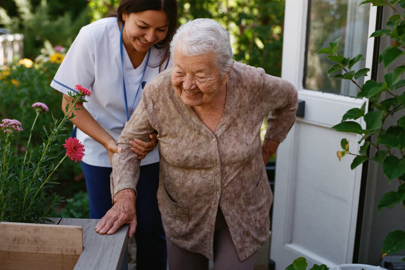 A nurse steadying an older woman as she walks up her porch steps