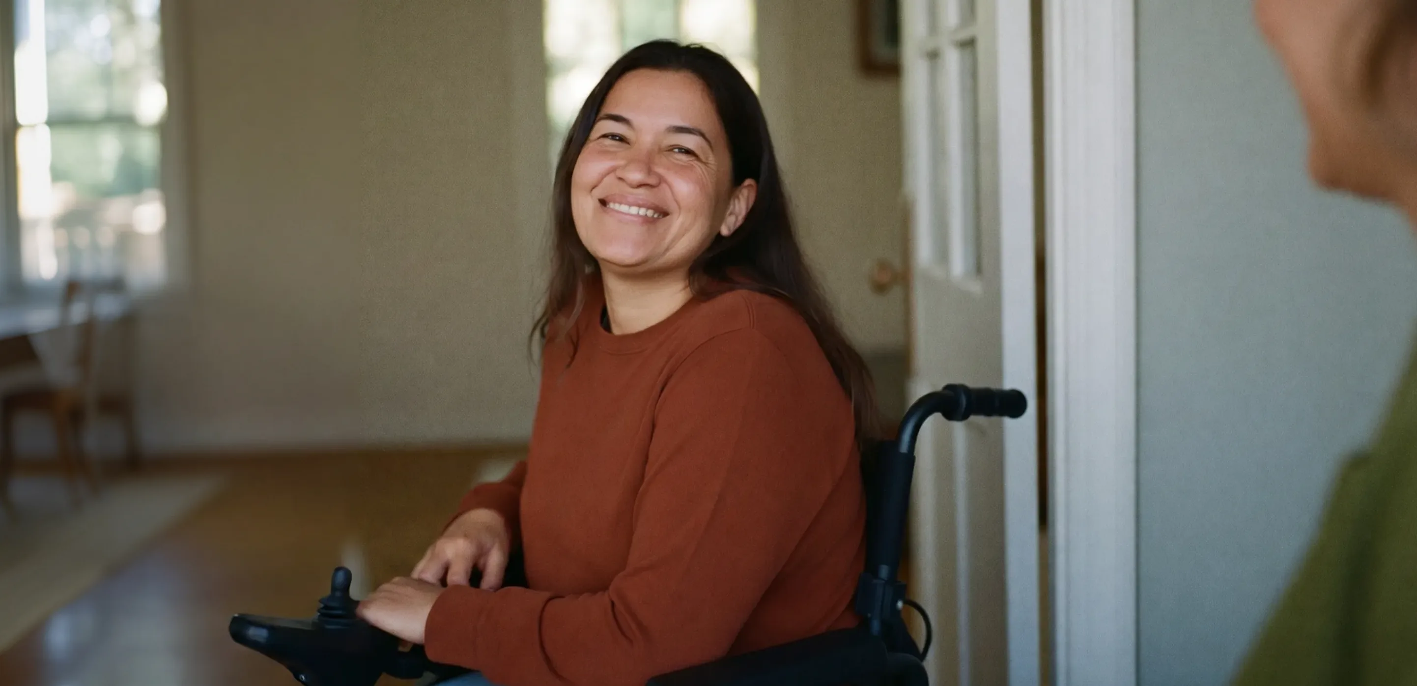 Catherine, a wheelchair user, smiling in the doorway of her home