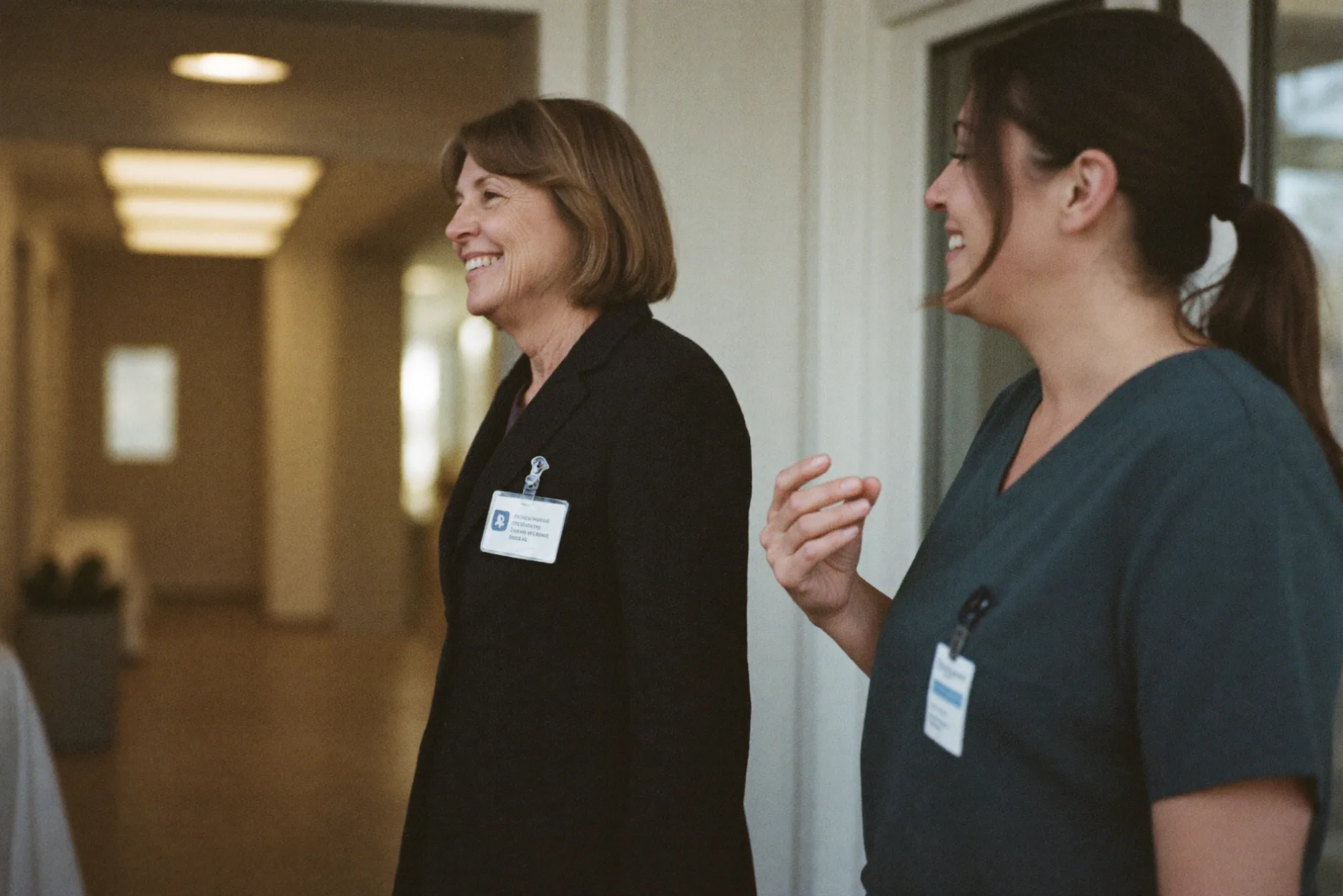 Two clinicians talking and smiling in a hospital corridor