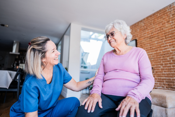 An OT kneeling next to a seated patient in the home