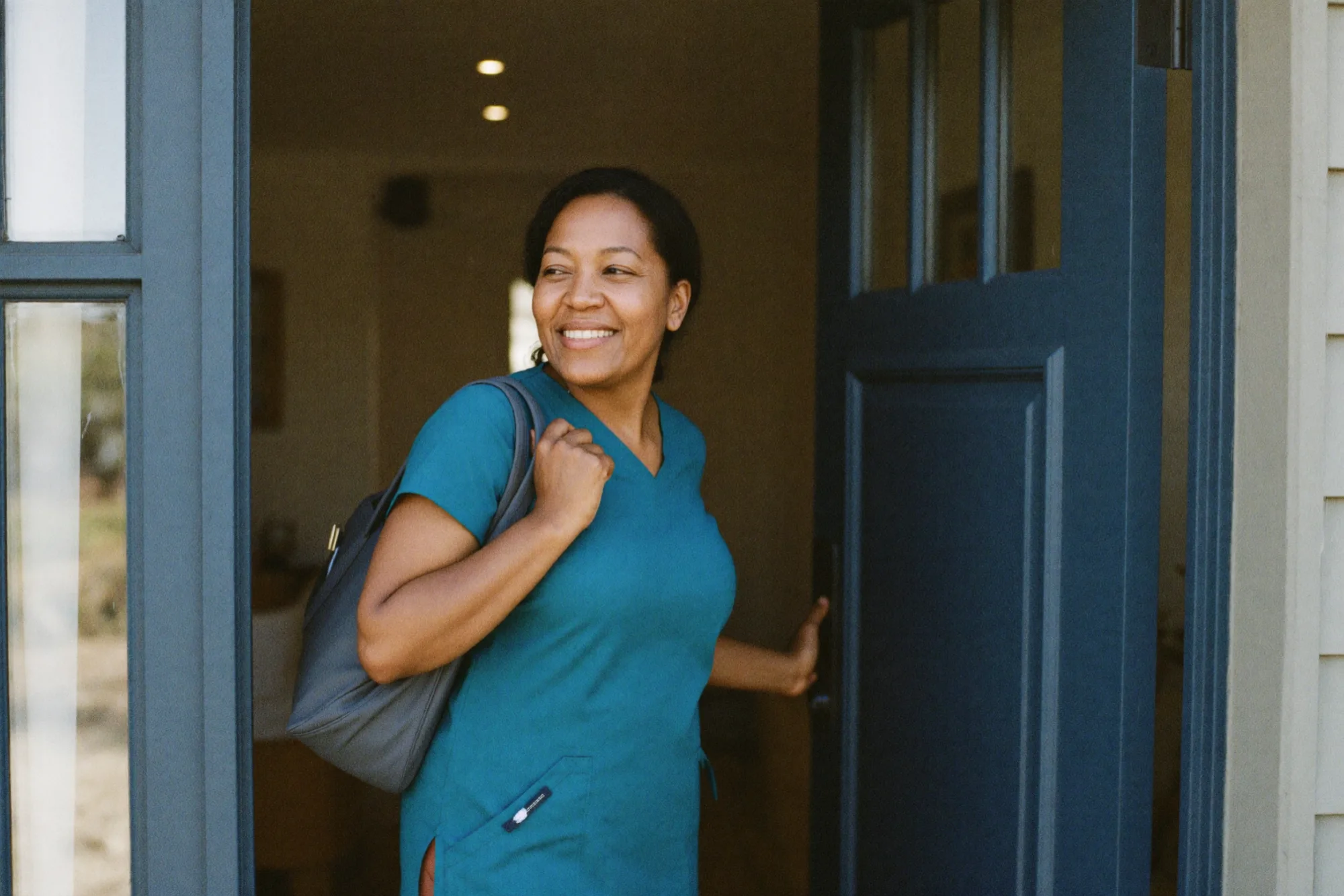 A home-health clinician smiling in the doorway of a member's home