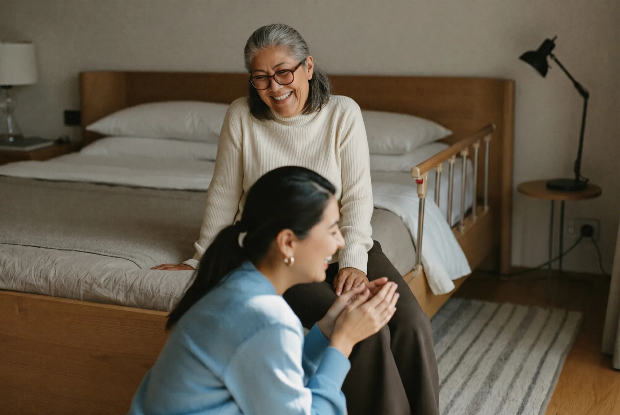 An older woman laughing with a family member at her bedside