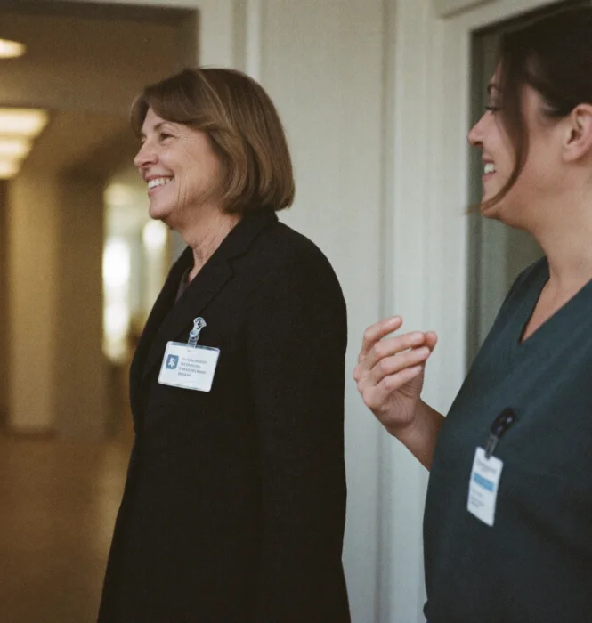 Two clinicians talking and smiling in a hospital corridor